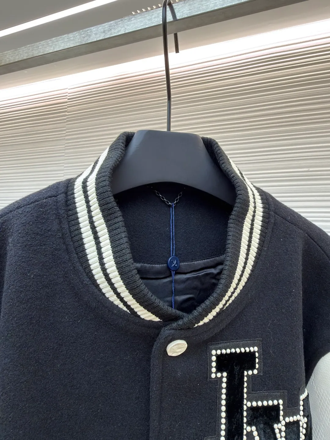 LOUIS VUITTON checkerboard embossed genuine leather and wool baseball jersey ●Original version: 51000 purchased and developed ●Item number: 1680926-i15 ●Fabric: genuine leather wool fabric ●Technology: embroidery ●Version: fitted version ●Weight: about 1770 grams ●Size: 44-46-48-50 ●Description: The fabric is made of 80% wool, with a weight of 750g. It is made of newly sheared wool and is dyed in reactive black in the vat. The colored cloth is bristle process. After brushing 5 times and washing 6 times, the fluffy surface fluff is trimmed flat, and the surface of the fabric appears fluffy. It has a hollow three-dimensional fluffy effect. You can feel the elasticity of the fabric when you touch and press it with your hands. The newly sheared wool yarn is long-fiber and is not easy to pill after shearing. The front and back panels are embroidered with Tajima embroidery machines imported from Japan. The nylon material is super matte and the tatami stitch method is multi-layered. Overlapping thread embroidery, the front chapter is made of viscose yarn, three-dimensional toothbrush embroidery, the mold is opened to determine the pile height and the suede is smoothed by hand, using acrylic round bubble beads, the surface of the bubble beads is sprayed three times, the base paint is latex paint, and the middle layer is sprayed with pearls Pearl white paint, the outer layer is sprayed with translucent glossy paint, the translucent bright white effect is completely comparable to that of mother-of-pearl. There are a total of 154 beads in the chapter. Each bead is dusted and positioned to ensure that it is flush with the edge of the chapter. The visual effect is not obtrusive. The two sleeves are made of water Made of dyed cowhide. Compared with spray-painted cowhide, there is nothing attached to the surface of water-dyed cowhide. Pure water-based dyes are continuously stirred in the tank to naturally color. During the period, samples are taken to compare the color of the Y-version sleeves according to the degree of coloring. When the colors are basically the same, they can be washed and dried naturally to produce the finished product. The thickness of the finished leather is 12mm. The embossing is made of a large-size aviation aluminum plate material mold. All the flowers are pressed according to the code positioning. An electric hydraulic control system is used, and the constant temperature and timing are automatically operated. The small sleeve logo is embossed separately from the small mold. It is pressed by electromagnetic pulse pressure and heating. After the sleeves are cut and embossed, the leather base is all shoveled to a thickness of 8mm. The leather thickness is reduced and the hand feels softer and closer to the body. The diamond-shaped plaid embossing on the surface causes an anti-skin phenomenon due to the thinning of the leather base. The pattern will naturally increase from the deep base state. Lightened, the diamond check pattern and the leather pebbles form a visually invisible effect. It is matched with cupro + cotton blended lining, the ribs are made of combed cotton yarn, and the horizontal loom imported from Taiwan has inter-color jacquard. It is matched with a custom-made molded aluminum alloy material with a logo spray-painted four-button buckle.